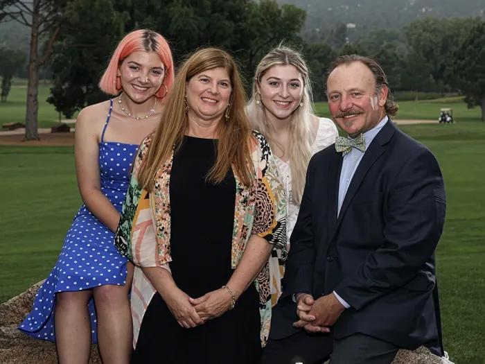 The Bonnell family, including Laura, Michael, and their two daughters, Emily and Molly, seated together with a golf course in the background.