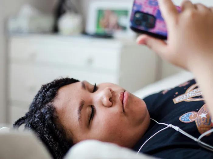 girl looking at phone laying in bed