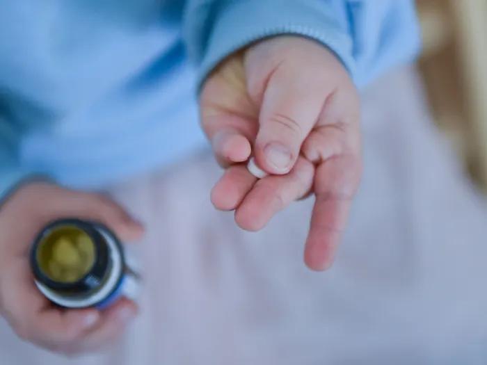 pill in child's hand blue sweater