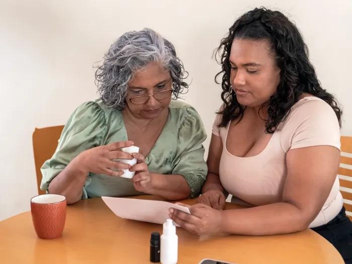 woman with older woman at table helping on tablet