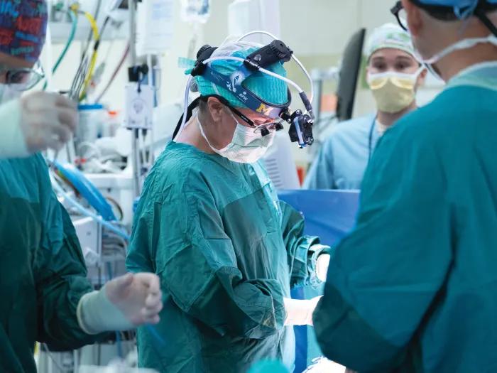 surgeon and surgical team set up in OR with teal gear on and masks