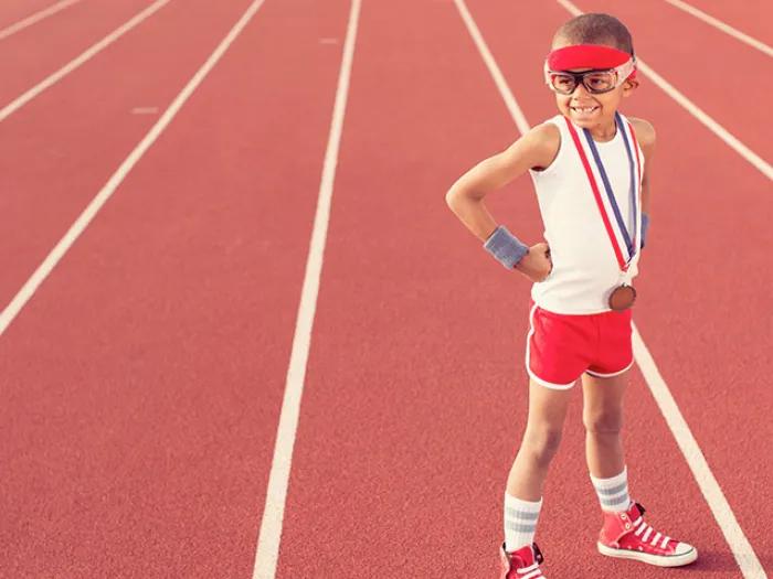 athlete boy in white shirt and red shorts on red track goggles medal 