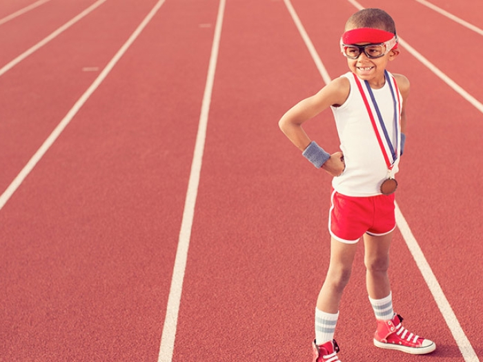 athlete boy in white shirt and red shorts on red track goggles medal 