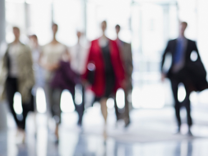 business people walking in white hallway blurred out from a distance