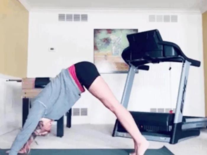 Girl doing downward dog yoga pose in her house