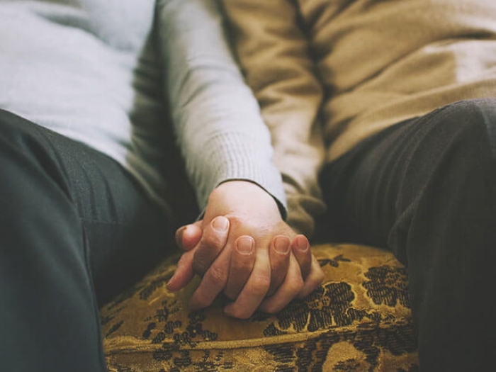 Couple holding hands while sitting low on couch