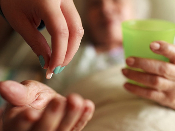 Cupped hand of elderly woman receiving pill