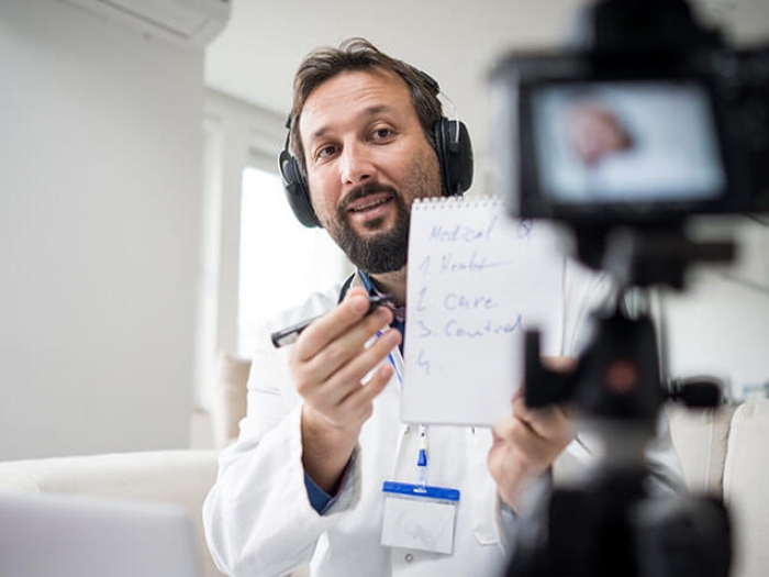 Doctor talking into camera in clinic holding notepad