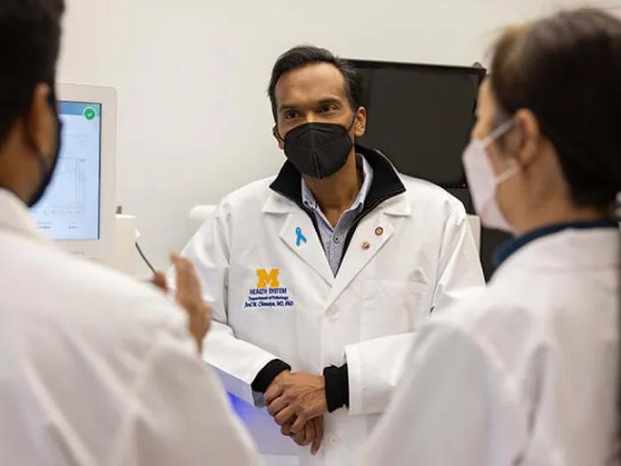 Doctors talking in office wearing white lab coats and masks. 