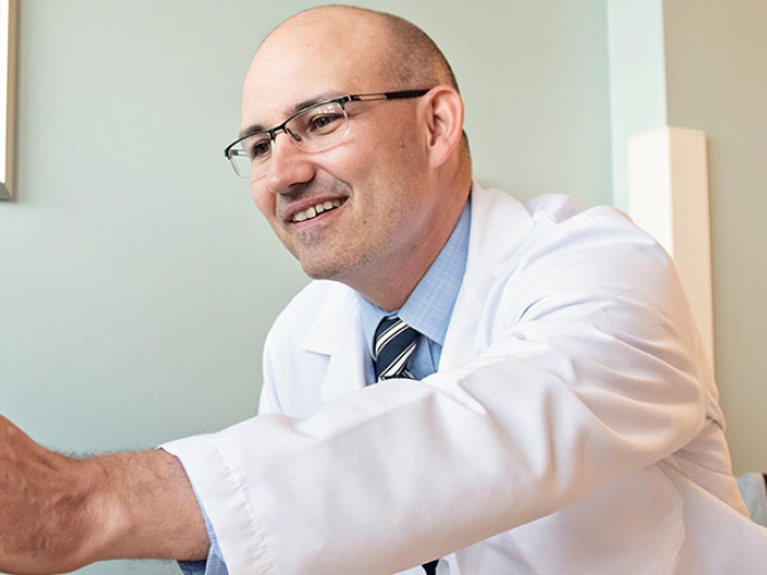 Doctor in room reaching out smiling