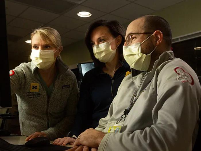 doctors masks pointing computer screen