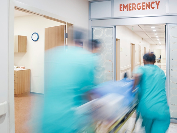 3 doctors rushing blurry into emergency room hospital in teal scrubs with stretcher