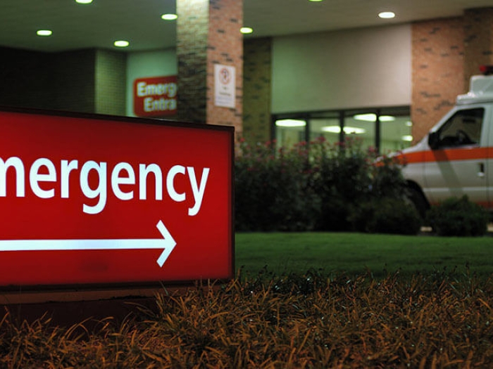 Emergency sign with hospital and ambulance in background