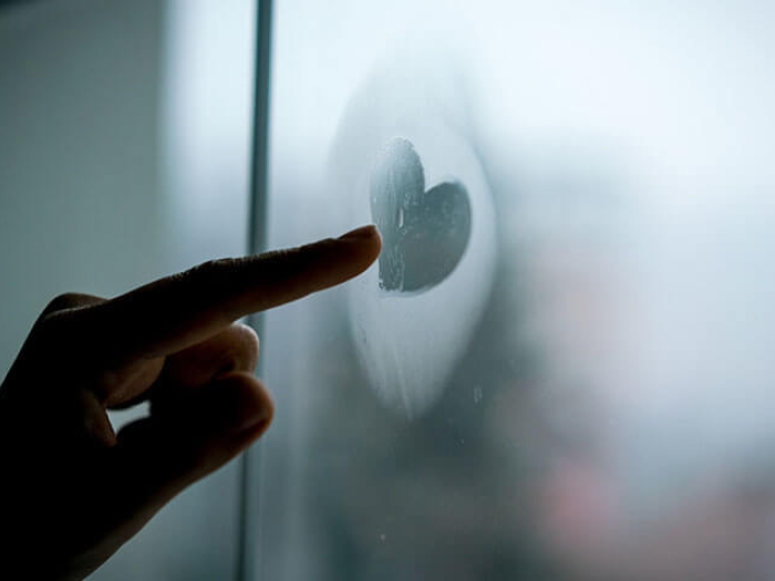 Finger touching heart on foggy window
