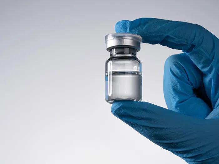 glove hand holding vaccine vial