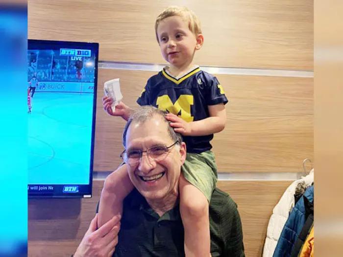 Grandpa with grandson on shoulders near a TV
