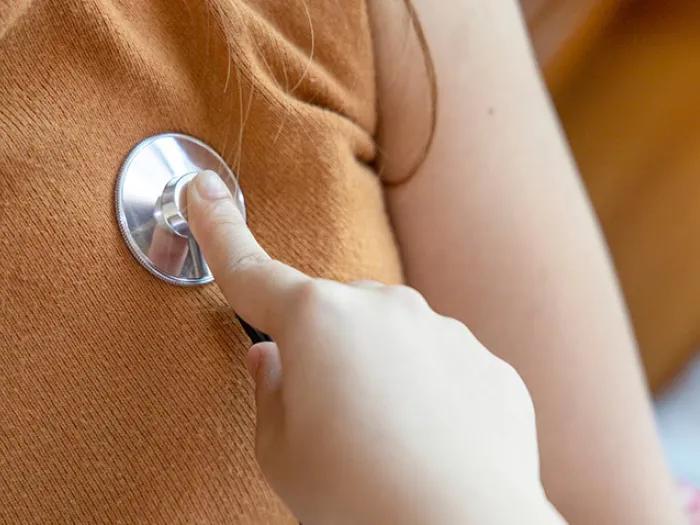stethoscope on heart of orange shirt close up