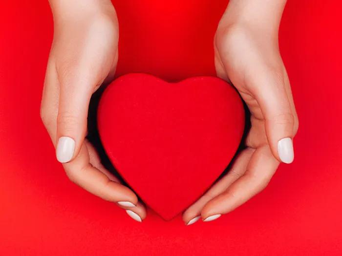 red heart held in hands in heart background