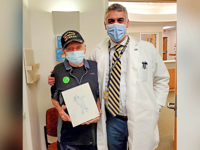 doctor and patient standing together holding the drawing