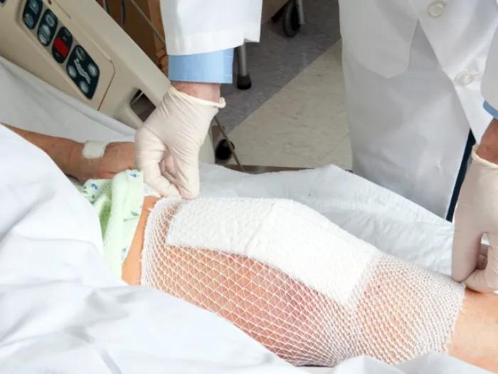 Doctor applying a bandage to a man's knee