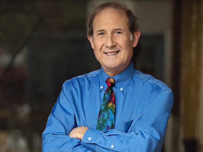 man smiling in rainbow tie in blue shirt