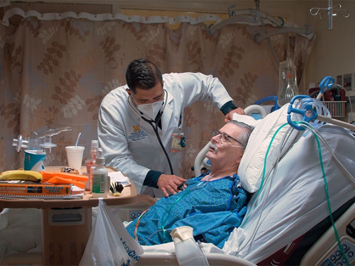 nurse standing at bedside with patient with mask on
