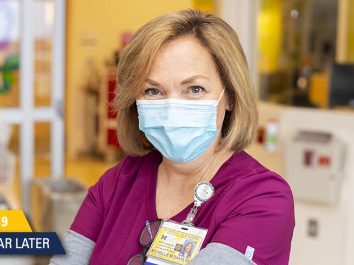 nurse in maroon scrubs and light blue mask smiling at camera