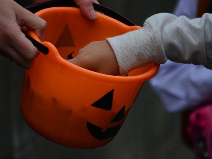 Orange pumpkin bag of candy with kids reaching inside