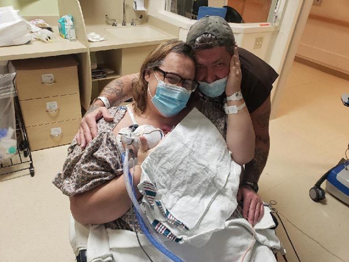 parents holding baby in hospital wheelchair