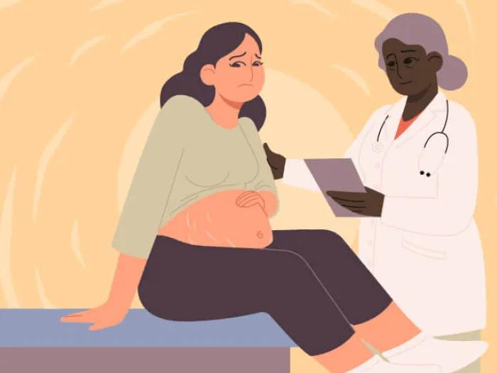 Pregnant woman sitting on edge of hospital bed talking with doctor