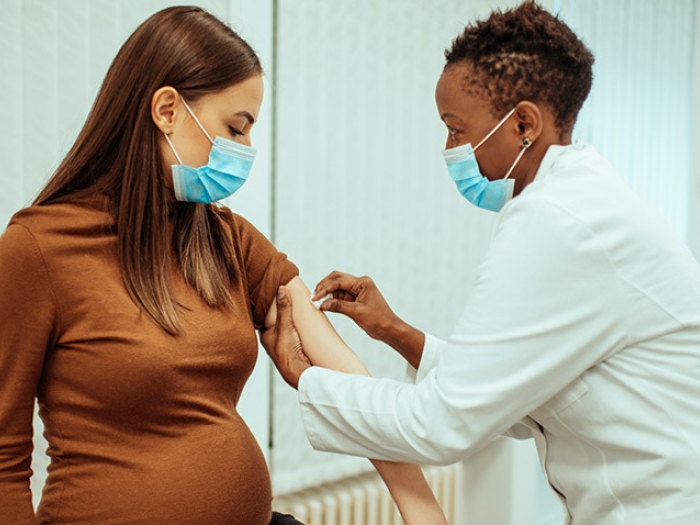 pregnant woman getting vaccine with doctor with masks on
