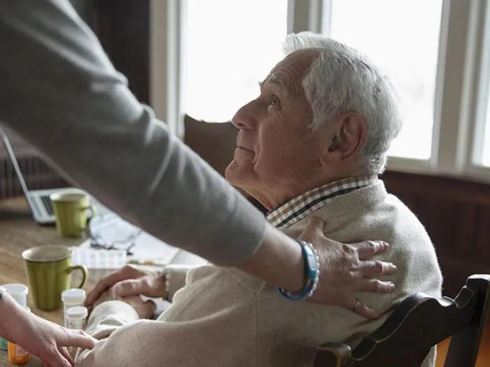 Elderly man with the hand of his support coach on his back