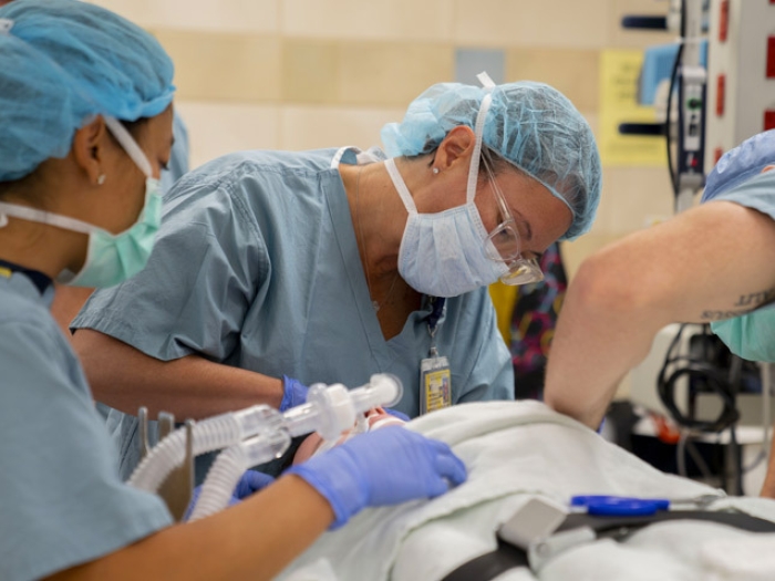 three surgeons in scrubs and masks intubating patient tub