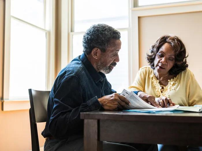 couple sitting at table with newspaper 
