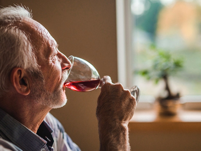 older man drinking red wine from glass