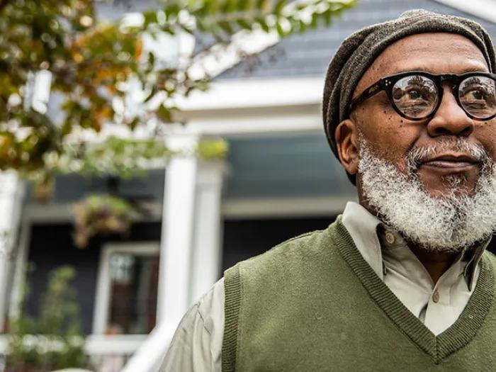 senior man wearing glasses house in background