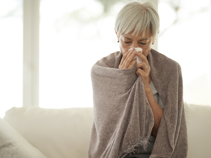senior woman blowing nose blanket
