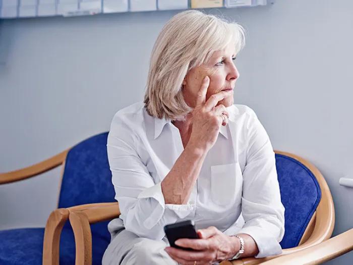 older woman sitting in chair looking at window in white shirt
