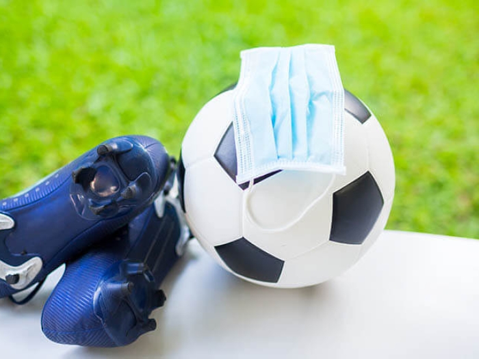 Soccer ball with cleats and mask near green field