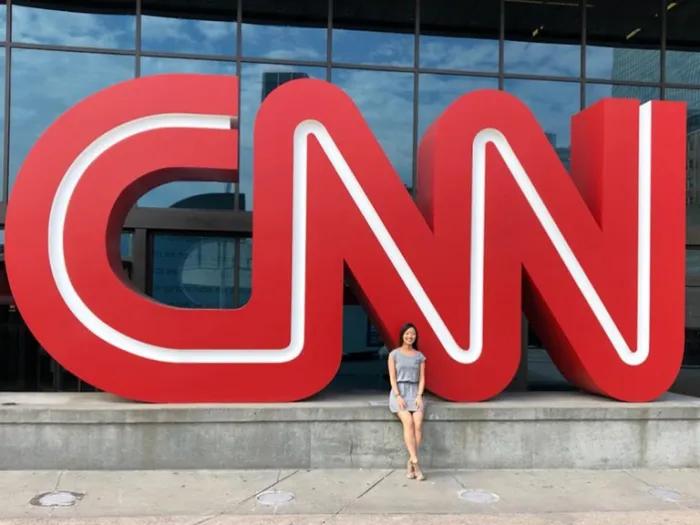 student in front of red CNN sign 
