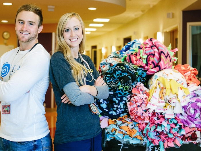 Tara and Nicholas Kristock and a pile of donated fleece blankets
