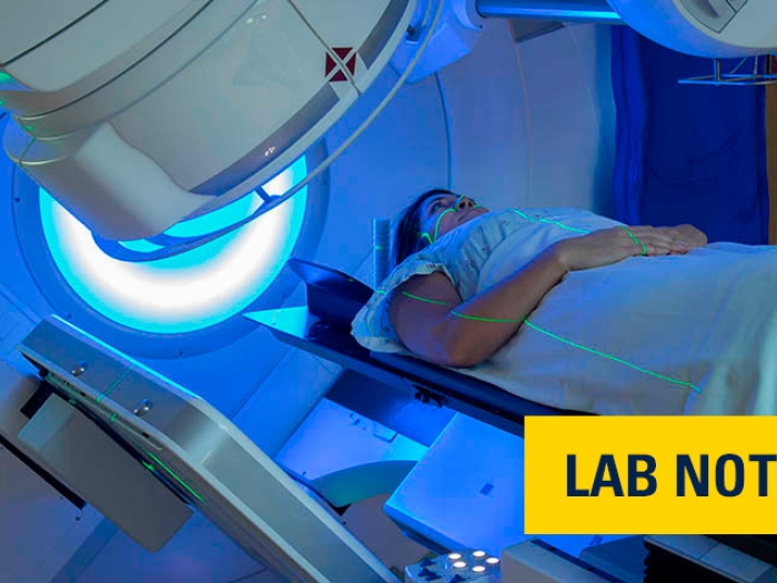 woman in hospital gown going under scan machine in blue light