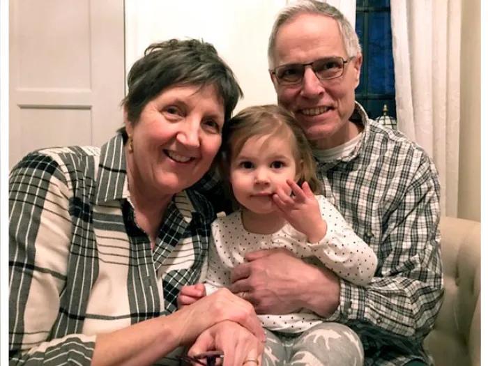 Woman and man wearing plaid smiling while holding child