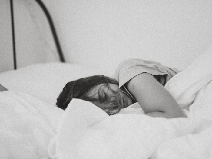 woman sleeping in bed with blanket in black and white photo