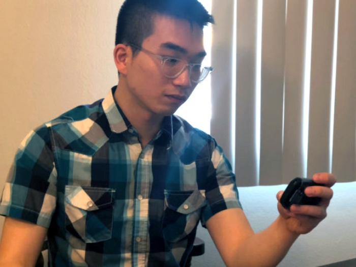 Young man in plaid shirt looking at pager
