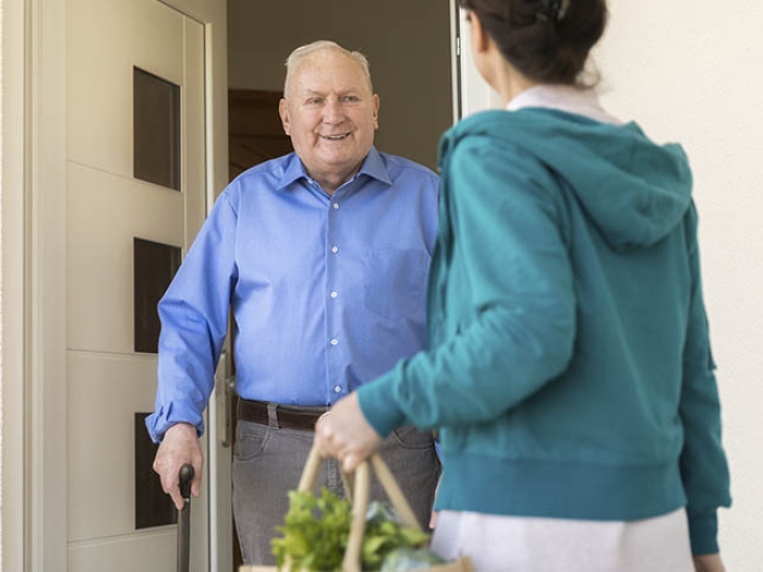 caregiver giving groceries to elderly gentleman