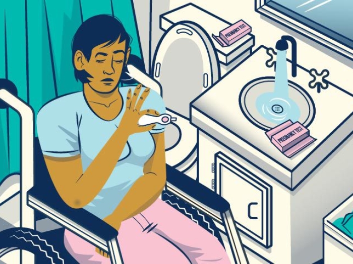 women in wheelchair looking at pregnancy test in bathroom with teal and pink and off-white muted colors