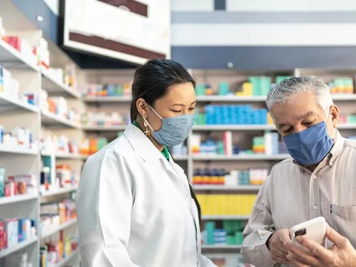 doctor helping gentleman looking at pills in pharmacy