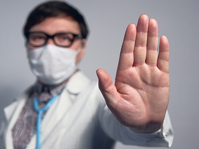 doctor holding hand up in mask with glasses and mask