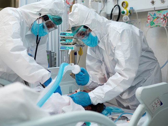 Doctors inserting ventilator tube hazmat suits